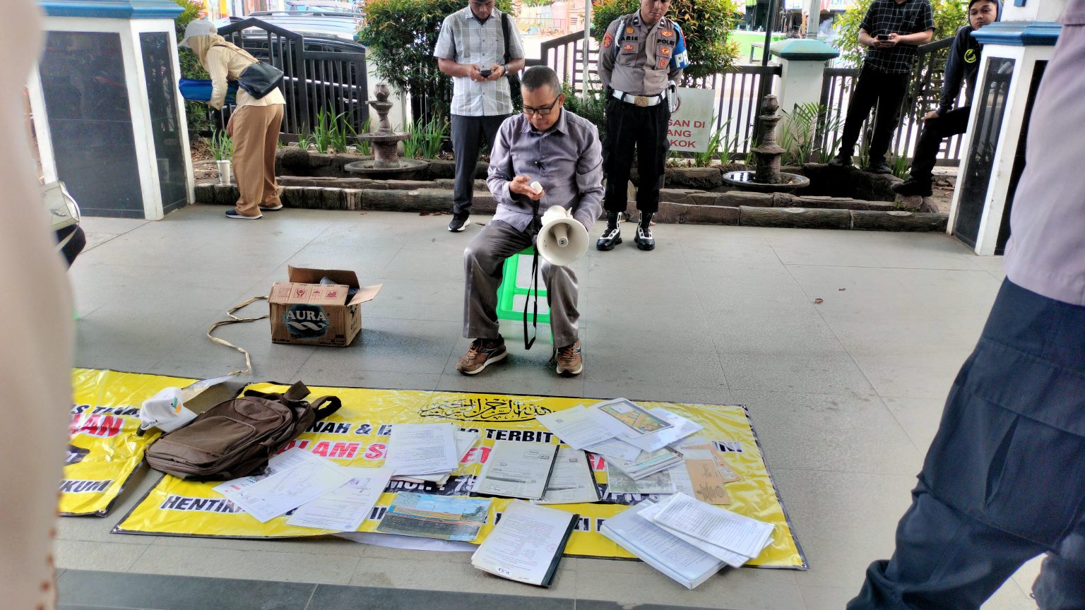 Warga Demo Terkait Perizinan PBG ALI Akbar sambil menghamparkan spanduk dan sejumlah berkas berdemo menuntut Dinas PUPR dan DPMPST, terkait perizinan PBG yang berdampak pada tanah miliknya.(foto:mb/ist)